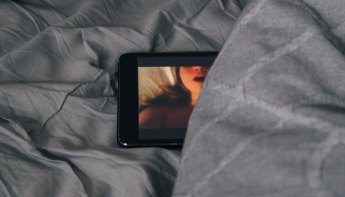 Une tablette est déposée sur un lit, une image de femme apparaît à l'écran. 