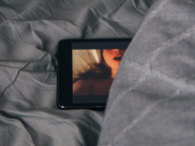 Une tablette est déposée sur un lit, une image de femme apparaît à l'écran. 